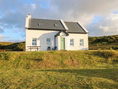 A house with green door and windows set in a garden at Doughbeg Beach Cottage in 