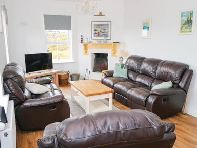 A living room with sofas and a coffee table at Doughbeg Beach Cottage 