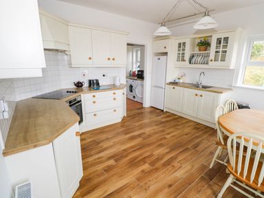 A kitchen with wooden flooring and appliances at Doughbeg Beach Cottage