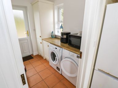 A laundry room with a washing machine and tumble dryer at Doughbeg Beach Cottage