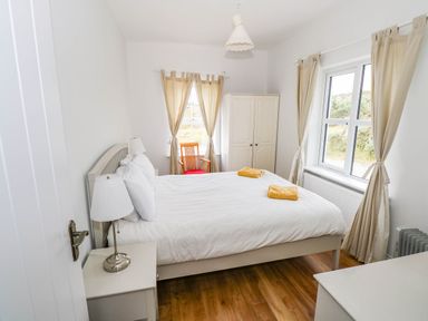 A bedroom with a bed and window at Doughbeg Beach Cottage