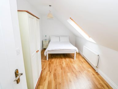 A bedroom with a bed and wardrobe at Doughbeg Beach Cottage