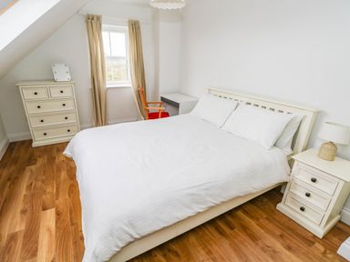 A bedroom with a bed and dresser at Doughbeg Beach Cottage