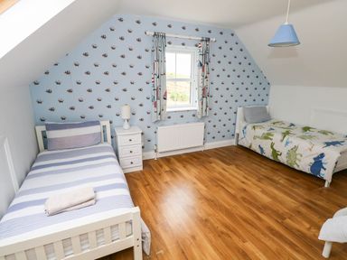 A bedroom with two beds and a window at Doughbeg Beach Cottage