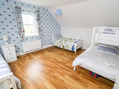A bedroom with beds and a window at Doughbeg Beach Cottage