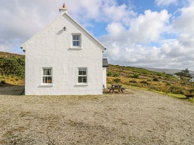 A house with windows and a door in a landscape at Doughbeg Beach Cottage 
