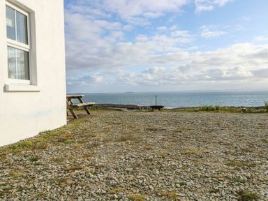 An outdoor area with a bench and sea view at Doughbeg Beach Cottage