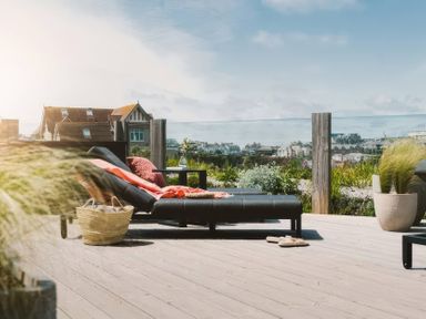 A lounge chair with a blanket and a basket on a deck at By The Sea in Newquay