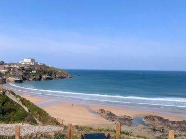 A beach with ocean waves and coastline at By The Sea in Newquay