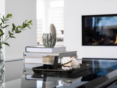 A living room with coffee cups and a tray of treats at By The Sea in Newquay