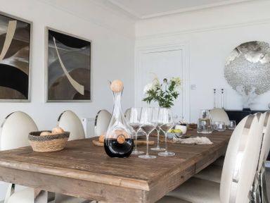 A dining room with a wooden table and glasses at By The Sea Newquay