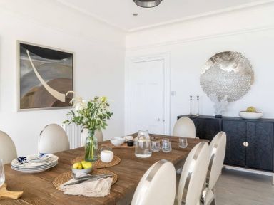 A dining room with a wooden table and chairs at By The Sea in Newquay