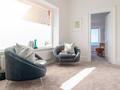A living room with armchairs and a table at By The Sea in Newquay