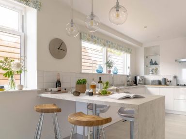A kitchen with a table and bar stools at By The Sea in Newquay
