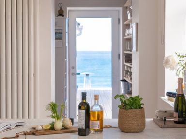 A kitchen with a table featuring bottles and garlic at By The Sea in Newquay