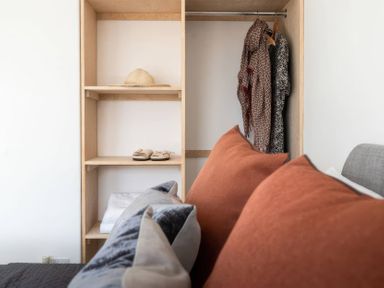 A bedroom with a shelf containing a hat, clothes, and slippers at By The Sea in Newquay