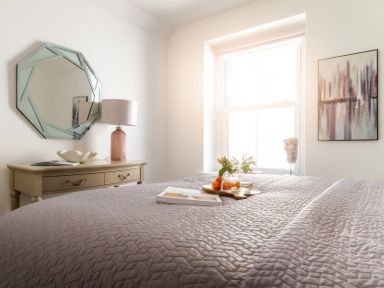 A bedroom with a bed, mirror, and drawer at By The Sea in Newquay
