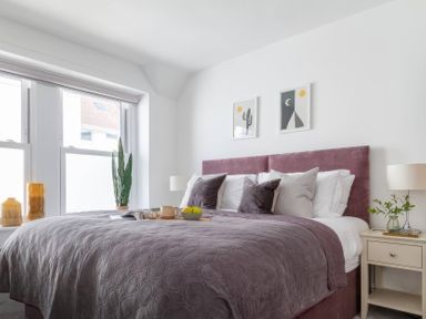 A bedroom with a bed, bedside table and cactus at By The Sea in Newquay