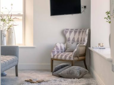 A living room with an armchair and television at By The Sea in Newquay