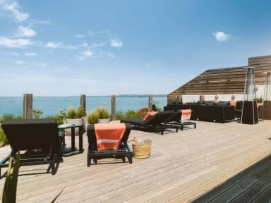 A deck with sun loungers and a coffee table at By The Sea in Newquay