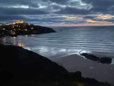 A beach with waves and rocks at By The Sea in Newquay