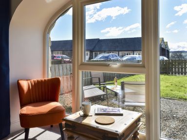 A living room with a window view of outdoor furniture at The Hayloft in Hexham