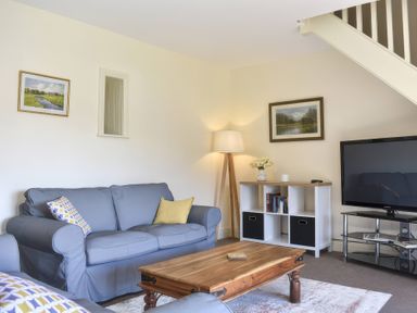 A living room with a sofa, table, and TV at The Hayloft in Hexham