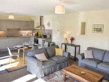 A living room with a sofa, coffee table, and kitchen area at The Hayloft in Hexham