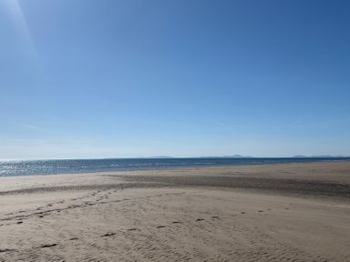 A beach with sand and ocean under a clear sky at Lyons Sunnysands - Snowdon Summit 050 in Talybont