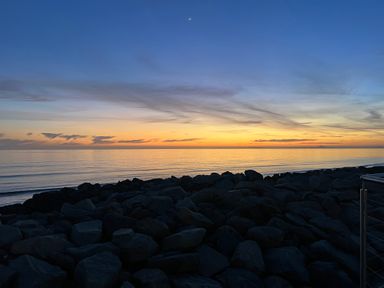 A view of the ocean and rocks during sunset at Lyons Sunnysands - Snowdon Summit 050 Talybont