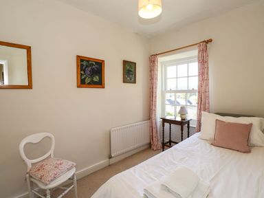 A bedroom with a bed and a chair at Jessicas Cottage in Windermere
