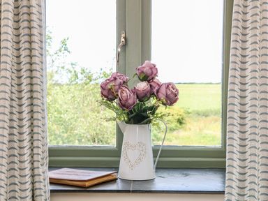 A window with a flower vase and book at Beech Cottage in Truro