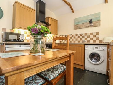 A kitchen with a washing machine and dining table at Beech Cottage in Truro
