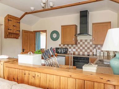 A kitchen with wooden cabinets and appliances at Beech Cottage in Truro