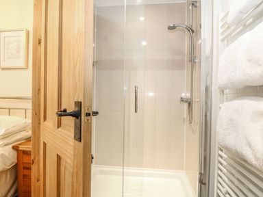 A shower with towels and a wooden door at Beech Cottage in Truro