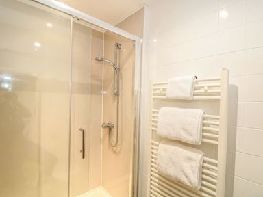 A bathroom with a shower and towel rack at Beech Cottage Truro
