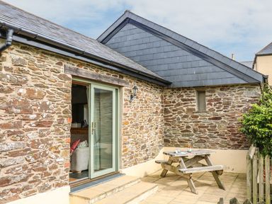 An outdoor area with stone wall and a wooden table at Beech Cottage in Truro