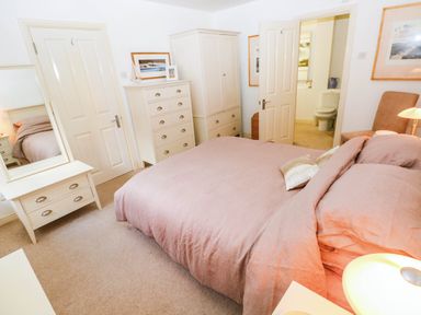 A bedroom with a bed and dresser at Basement Apartment in Tenby