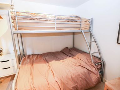 A bedroom with a bunk bed and bedding at Basement Apartment in Tenby