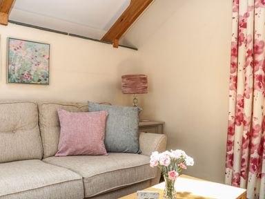 A living room featuring a sofa with cushions and a vase with flowers at Oak Cottage in Truro