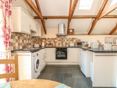 A kitchen with appliances and wooden beams at Oak Cottage in Truro