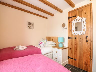 A bedroom with two beds and a side table at Oak Cottage in Truro