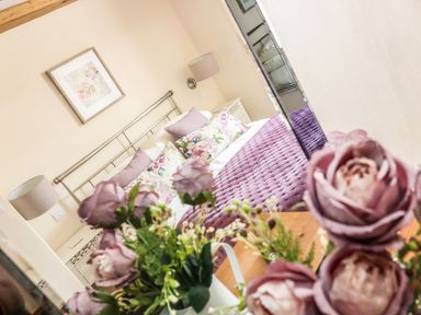 A bedroom with a bed and floral decor at Oak Cottage in Truro