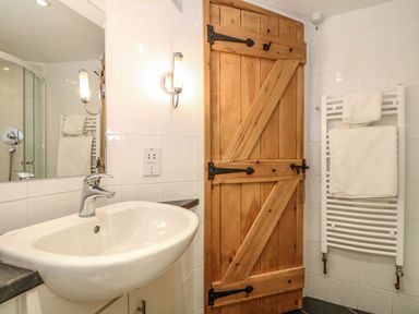 A bathroom with a sink and wooden door at Oak Cottage, Truro