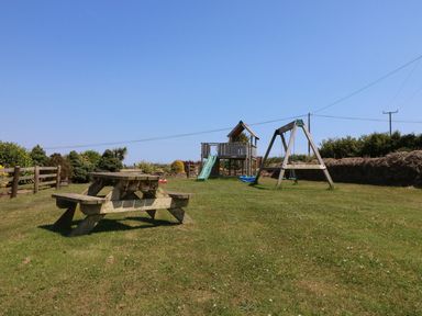 A garden with a picnic table and play equipment at Oak Cottage in Truro