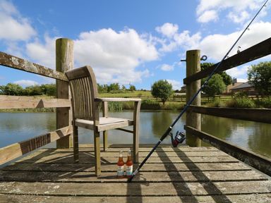 A dock with a chair and fishing rod next to water at Oak Cottage in Truro