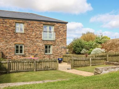 A garden with a stone building and wooden fence at Hawthorn Cottage in Truro