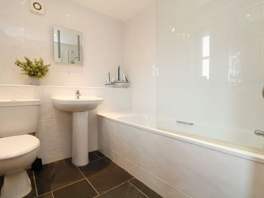 A bathroom with a sink, toilet, and bathtub at Hawthorn Cottage in Truro