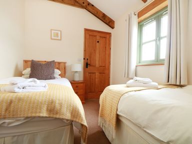 A bedroom with two beds and a window at Hawthorn Cottage in Truro