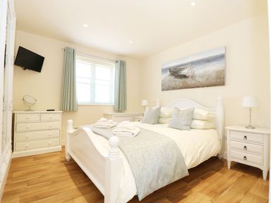 A bedroom with a bed, dresser, and television at Elm Cottage in Truro